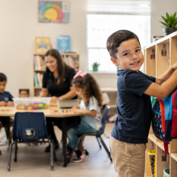 Child hanging backpack in preschool classroom, building confidence and kindergarten readiness